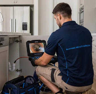 Plumber clearing a blocked toilet in a Harrington Park bathroom